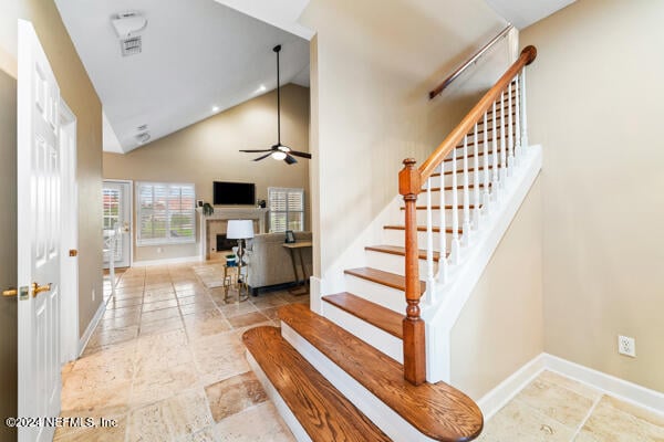 stairway with ceiling fan and high vaulted ceiling