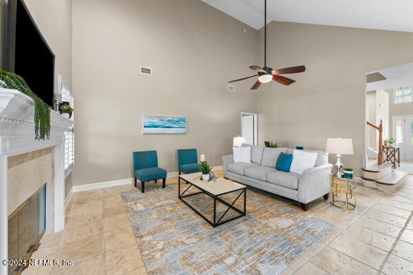 living room with a wealth of natural light, ceiling fan, and high vaulted ceiling