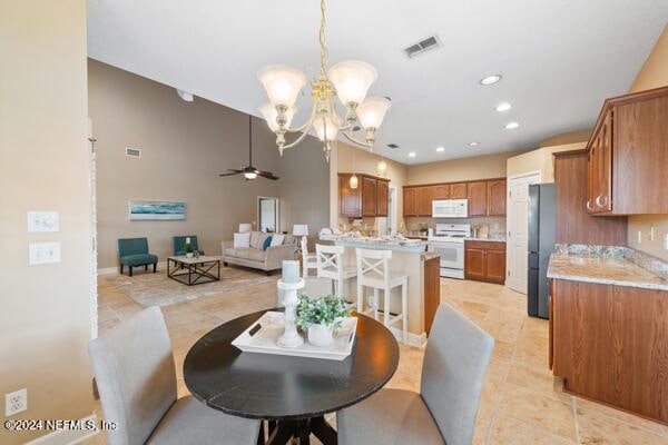 dining space with ceiling fan with notable chandelier and light tile patterned floors