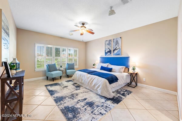 tiled bedroom featuring ceiling fan and a textured ceiling