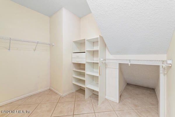 spacious closet featuring light tile patterned floors and lofted ceiling