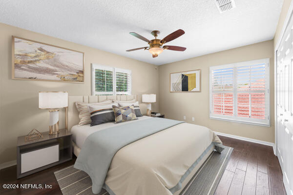 bedroom with a textured ceiling, ceiling fan, a closet, and dark hardwood / wood-style floors