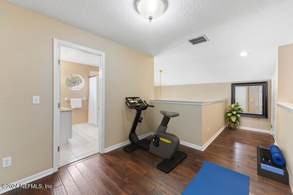 workout room with a textured ceiling, dark hardwood / wood-style flooring, and vaulted ceiling