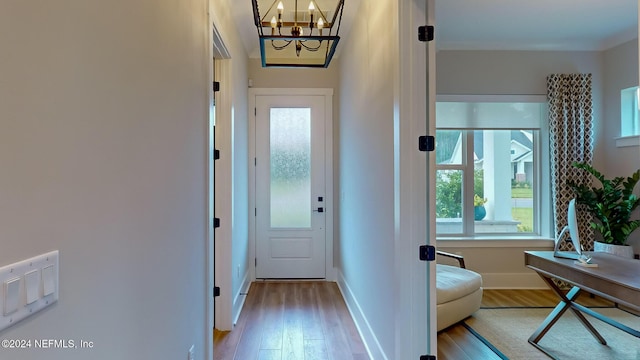 doorway with a notable chandelier, baseboards, and wood finished floors