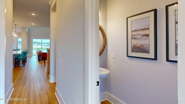 hallway featuring light wood-style flooring, baseboards, and recessed lighting