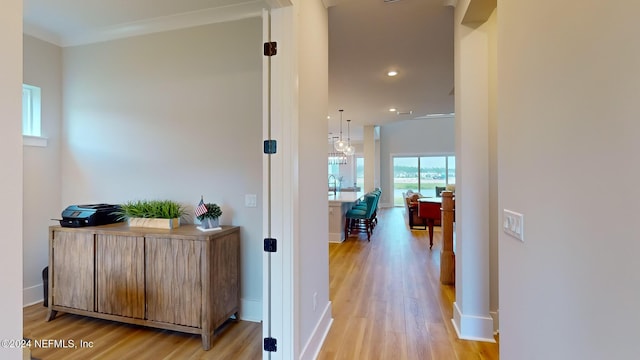 hallway featuring light wood-style floors, recessed lighting, crown molding, and baseboards