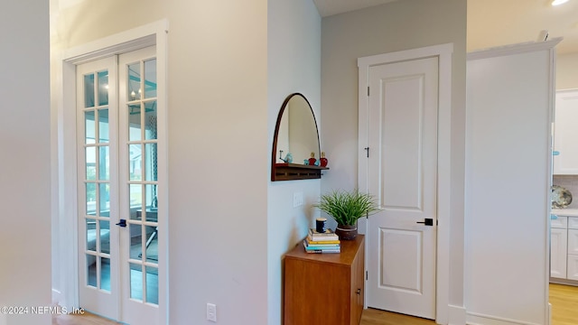 corridor with light wood-style floors and french doors