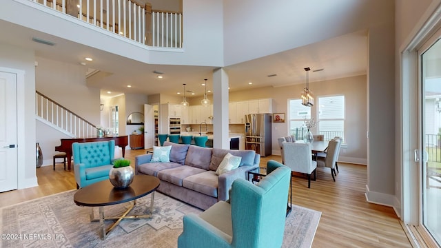 living area featuring light wood-style flooring, recessed lighting, a towering ceiling, visible vents, and baseboards