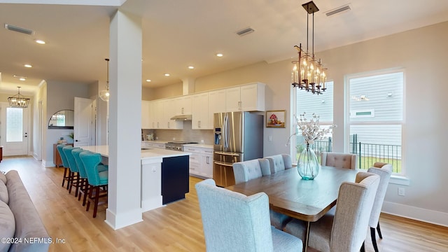 dining room featuring a healthy amount of sunlight, visible vents, and a notable chandelier