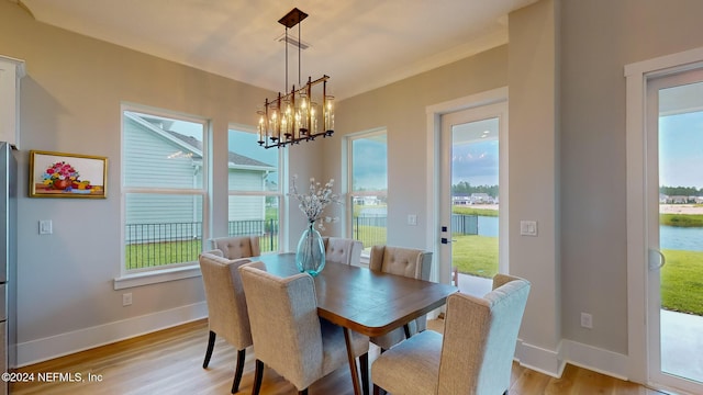 dining area featuring a water view, light wood finished floors, baseboards, and a chandelier