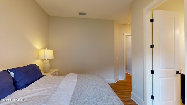 bedroom with visible vents, baseboards, and wood finished floors