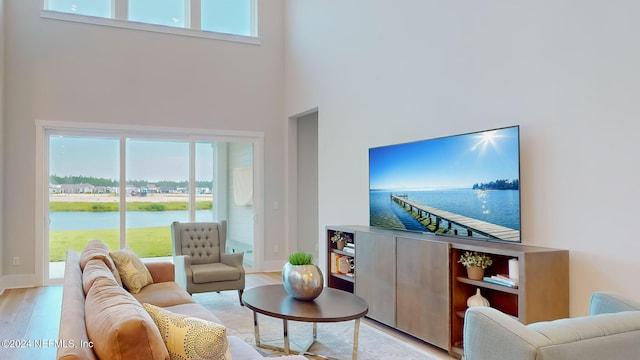 living room with light wood-type flooring and a towering ceiling