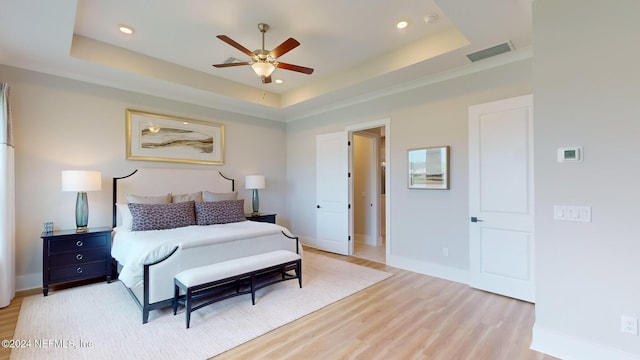 bedroom featuring light wood-style flooring, recessed lighting, visible vents, baseboards, and a tray ceiling