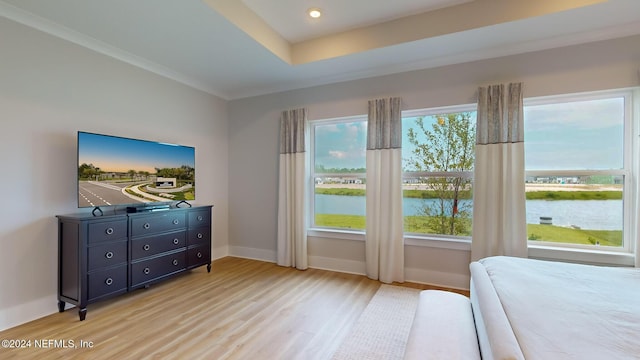 bedroom with a water view, light wood-style flooring, multiple windows, and baseboards