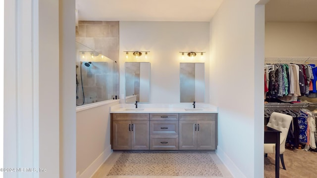 full bath featuring a walk in closet, a walk in shower, a sink, and double vanity