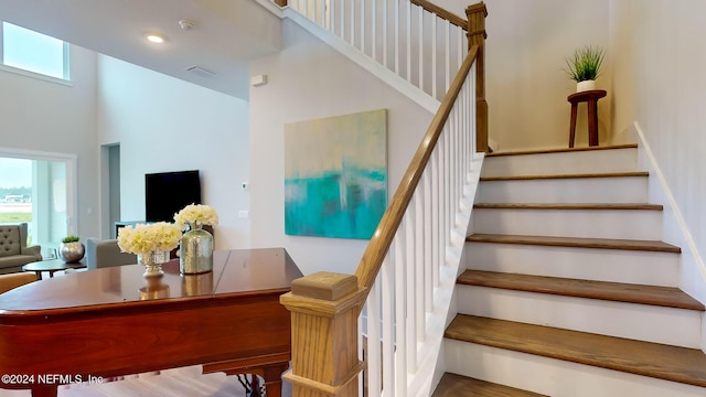 staircase featuring recessed lighting, visible vents, and a towering ceiling