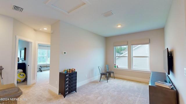 living area with a healthy amount of sunlight, attic access, visible vents, and light colored carpet