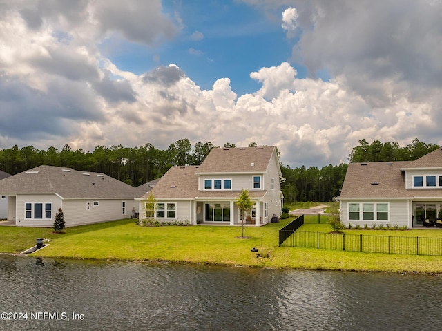 back of house featuring a water view, fence, and a lawn