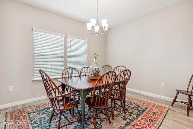 dining area with light hardwood / wood-style floors and a notable chandelier