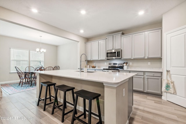 kitchen with a kitchen island with sink, gray cabinets, appliances with stainless steel finishes, and sink