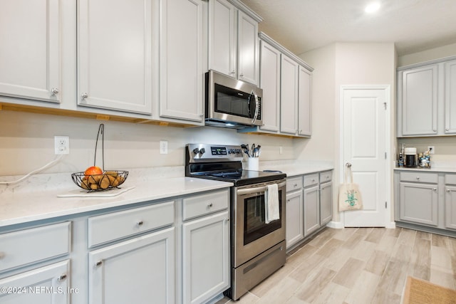 kitchen featuring appliances with stainless steel finishes, gray cabinetry, and light hardwood / wood-style flooring