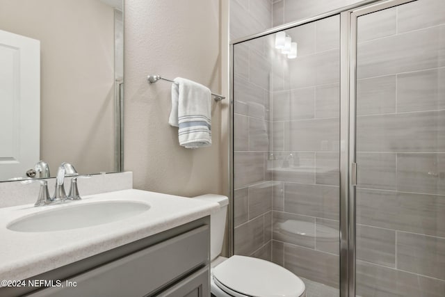 bathroom featuring a shower with shower door, vanity, and toilet