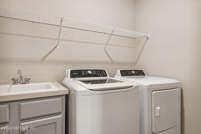 washroom with washer and clothes dryer, cabinets, and sink