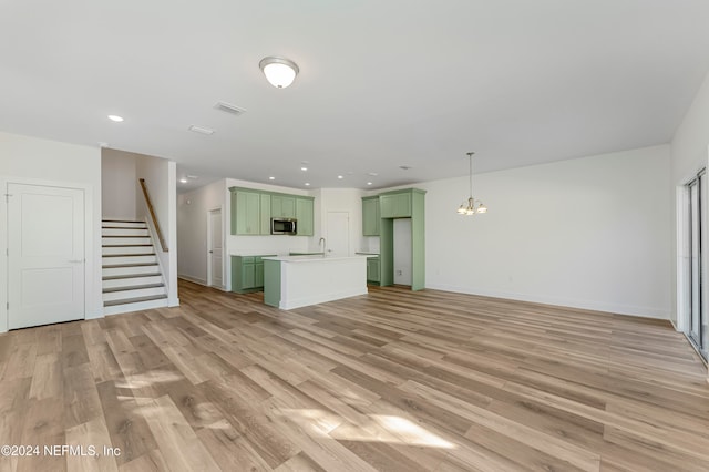 unfurnished living room featuring sink, a notable chandelier, and light wood-type flooring