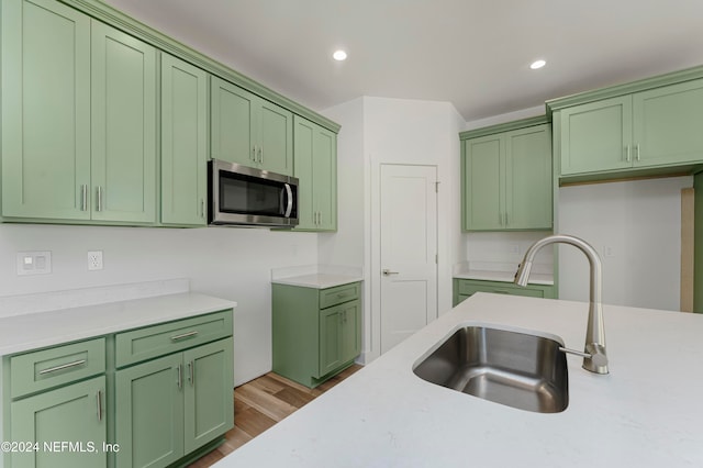 kitchen with green cabinets, hardwood / wood-style floors, and sink