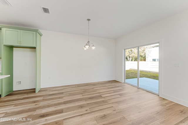 unfurnished dining area with light hardwood / wood-style floors and an inviting chandelier