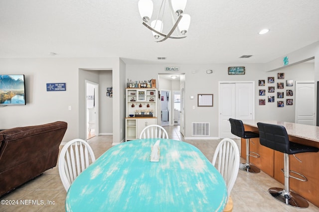 tiled dining space featuring a chandelier and a textured ceiling