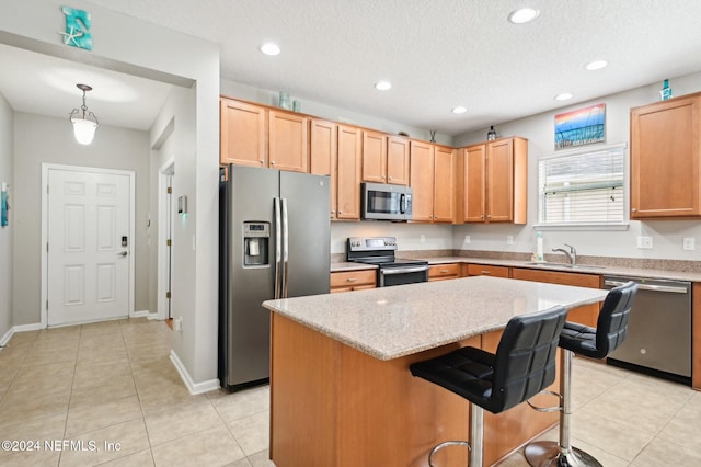 kitchen with light stone countertops, a center island, sink, stainless steel appliances, and pendant lighting