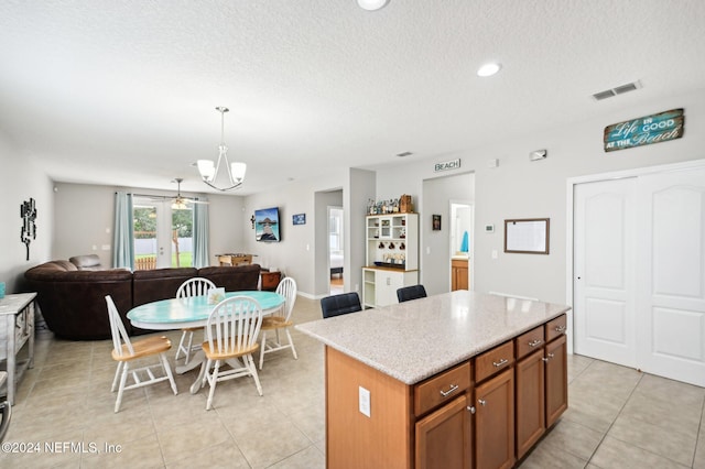 kitchen featuring pendant lighting, a center island, light tile patterned floors, and a notable chandelier