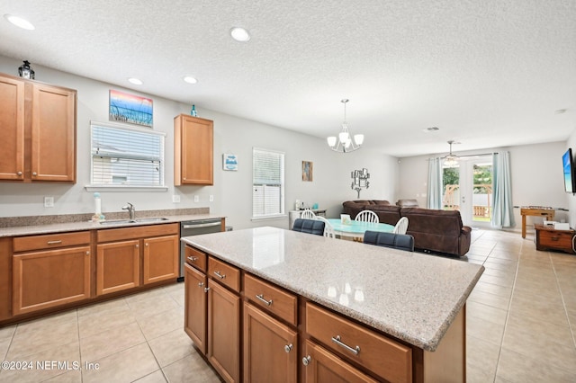 kitchen with pendant lighting, a center island, sink, light tile patterned floors, and a textured ceiling