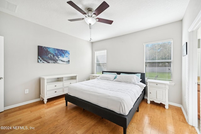 bedroom with ceiling fan, light hardwood / wood-style flooring, and a textured ceiling