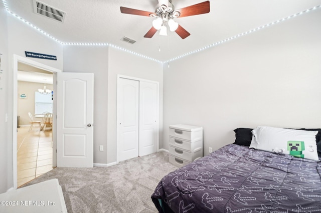 carpeted bedroom featuring a closet and ceiling fan with notable chandelier