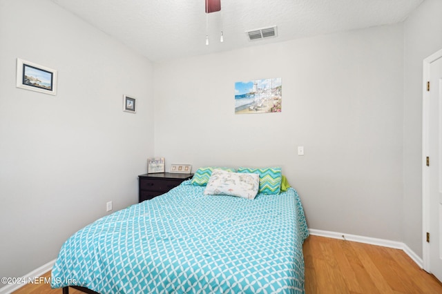 bedroom featuring hardwood / wood-style floors, a textured ceiling, and ceiling fan