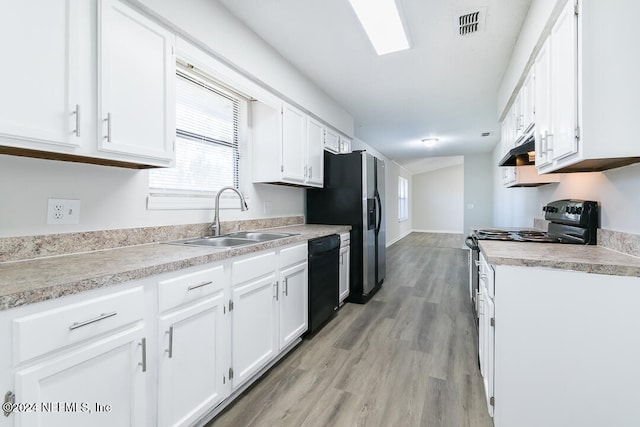 kitchen with black appliances, white cabinetry, sink, and light hardwood / wood-style flooring