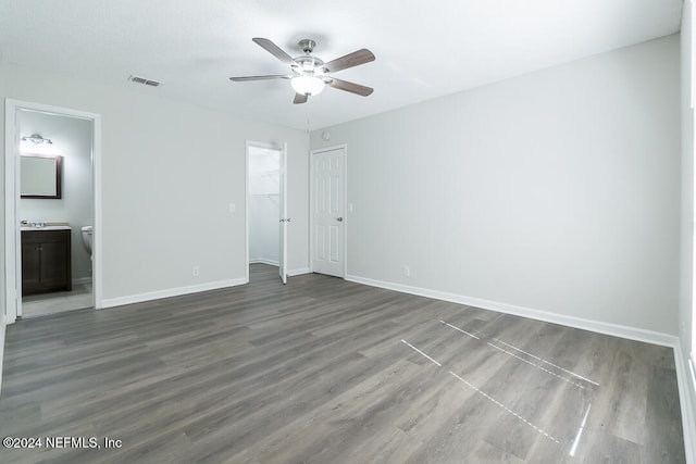 unfurnished bedroom featuring connected bathroom, dark hardwood / wood-style floors, and ceiling fan