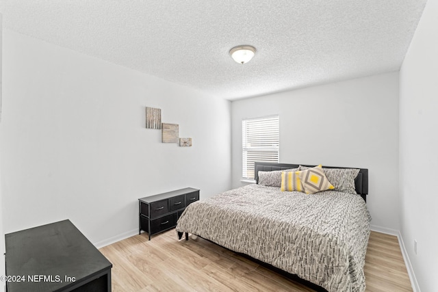 bedroom with light wood-type flooring and a textured ceiling