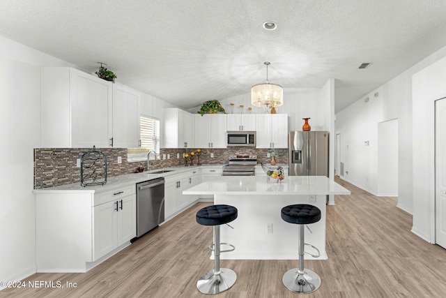 kitchen featuring white cabinetry, sink, a center island, pendant lighting, and appliances with stainless steel finishes