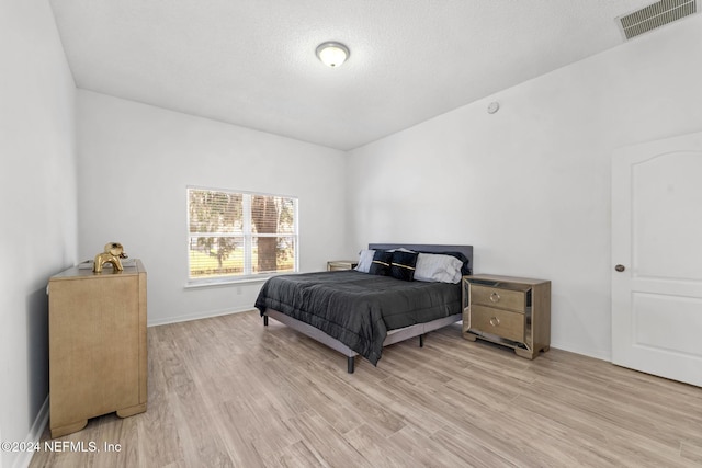 bedroom featuring light hardwood / wood-style floors and a textured ceiling