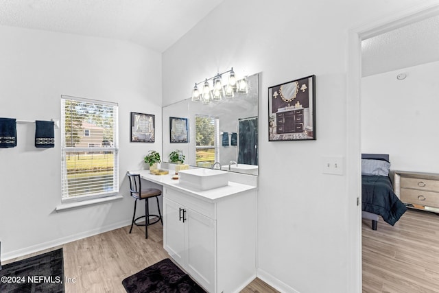 bathroom featuring a textured ceiling, vanity, hardwood / wood-style flooring, and lofted ceiling