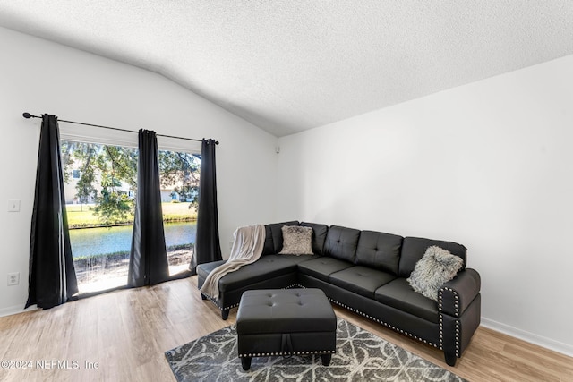 living room featuring a textured ceiling, a water view, wood-type flooring, and lofted ceiling