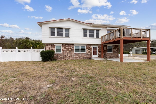 back of property with a lawn, a wooden deck, and a patio