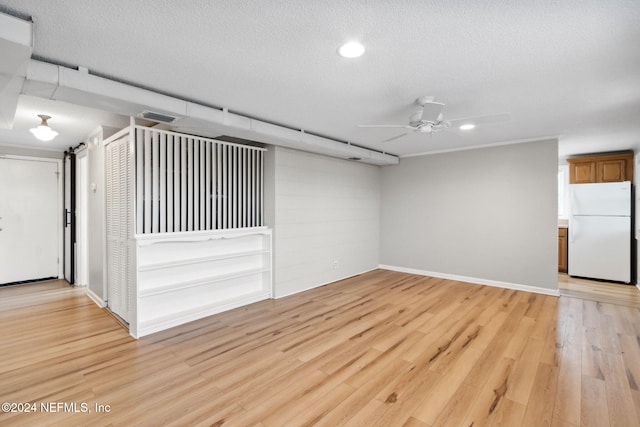 empty room featuring ceiling fan, a textured ceiling, and light hardwood / wood-style floors