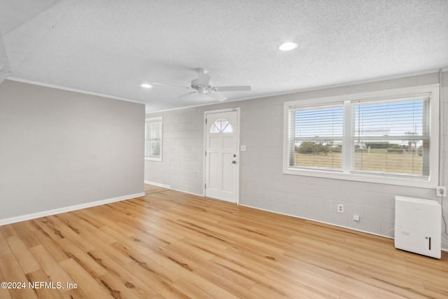 foyer entrance featuring ornamental molding, light wood-type flooring, a textured ceiling, and ceiling fan