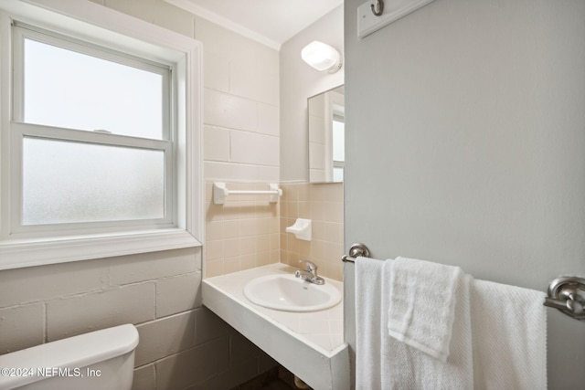 bathroom with toilet, tile walls, and sink