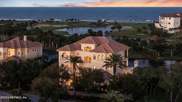 aerial view at dusk featuring a water view