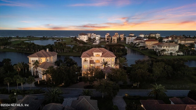 aerial view at dusk featuring a water view